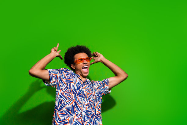 照片时髦酷的家伙穿着印花衬衫深色眼镜跳舞唱歌空空间孤立的绿色背景图片下载