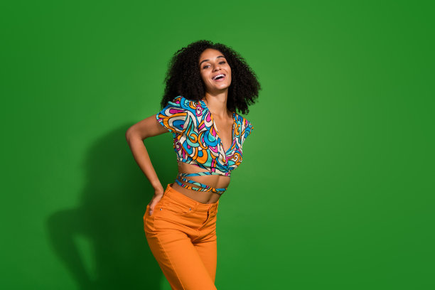 照片中，优雅积极的年轻女性模特穿着时尚的服装，在绿色的背景下微笑着爱夏天图片下载