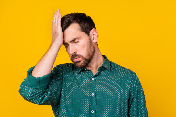 照片中的疲惫不堪的男人，时尚的发型，穿着带点的衬衫，头痛，感觉不好孤立在黄色的背景图片下载