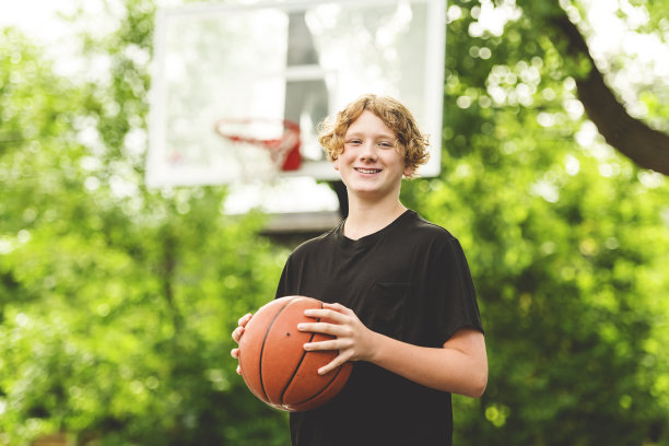 一个男孩在公园里打篮球的照片图片下载