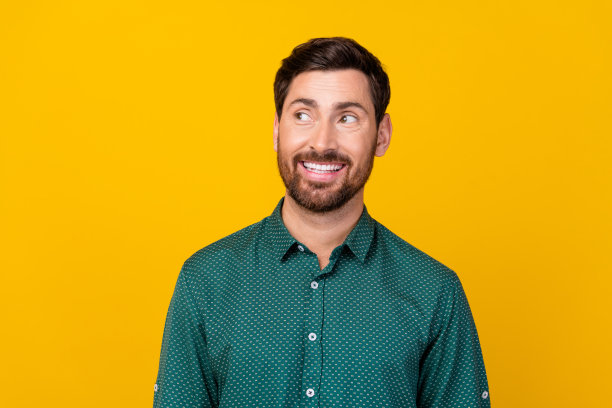 照片的好心情英俊的男人与深色头发穿着点衬衫看宣传空白空间孤立在黄色的背景图片下载