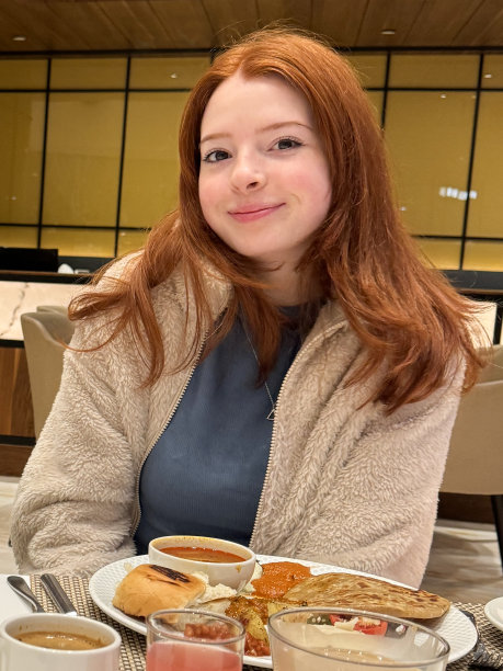 特写照片中，迷人的红发女子穿着便服，坐在自助服务的混合早餐盘前，餐厅设置为背景，焦点在前景图片下载