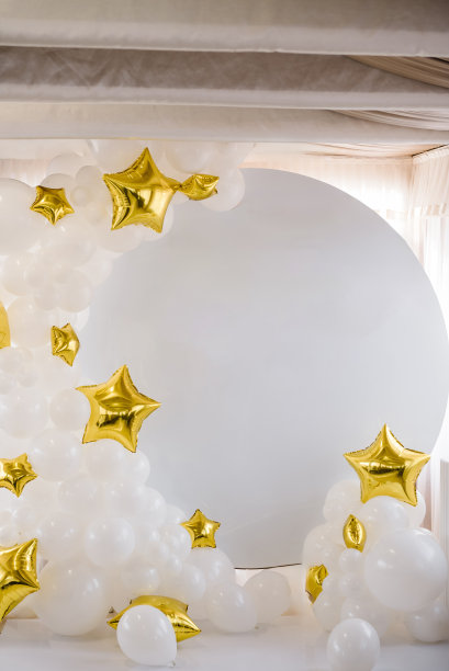 拱门上装饰着星星形状的白色金色气球。庆祝洗礼的概念。宝宝生日派对的接待处挂在墙上。金色风格的照片区。白色的墙壁或背景有文字的地方图片下载