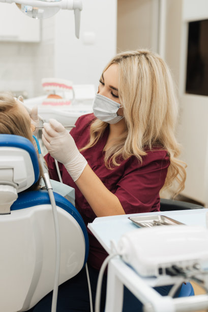 牙医开始为一位女士做常规的口腔清洁手术。垂直的照片。图片下载