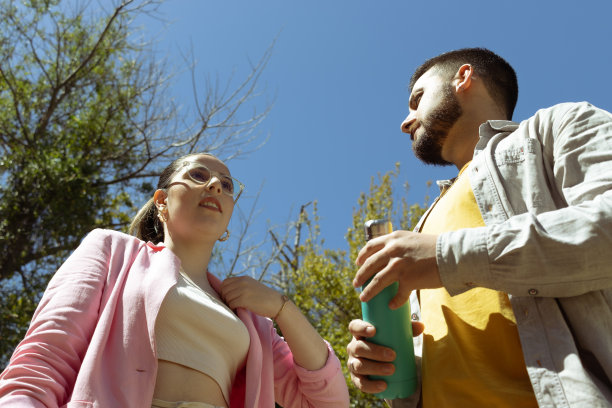 两个年轻人在阳光下拿着一个热水瓶。图片下载