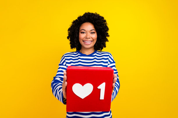 照片中，迷人的积极可爱的博主女孩穿着时尚的条纹衣服，在黄色的背景上展示了红牌图片下载