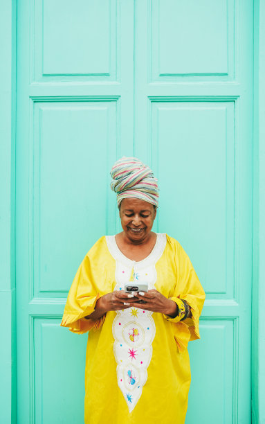非洲老年妇女穿着传统民族服装使用手机-技术，民族和成熟的人的概念-垂直照片图片下载
