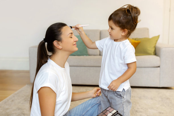 可爱的小女孩在家里玩的时候给妈妈化妆图片下载