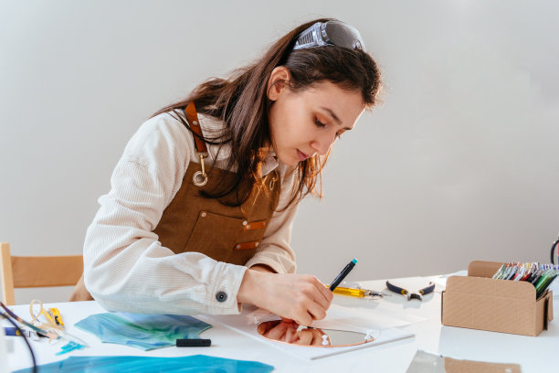 年轻女性彩色玻璃艺术家在工作室工作。彩色玻璃艺术，玻璃作品工艺。艺术创意，手工制作，爱好和工艺概念。图片下载