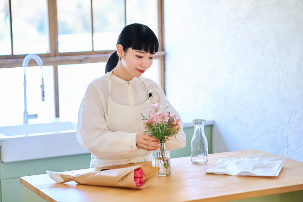 年轻女子欣赏花瓶里的花图片下载