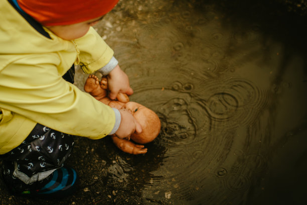 小男孩在雨中玩耍的照片图片下载