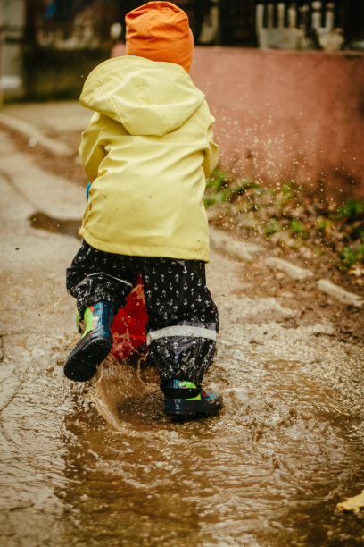 小男孩在雨中玩耍的照片图片下载