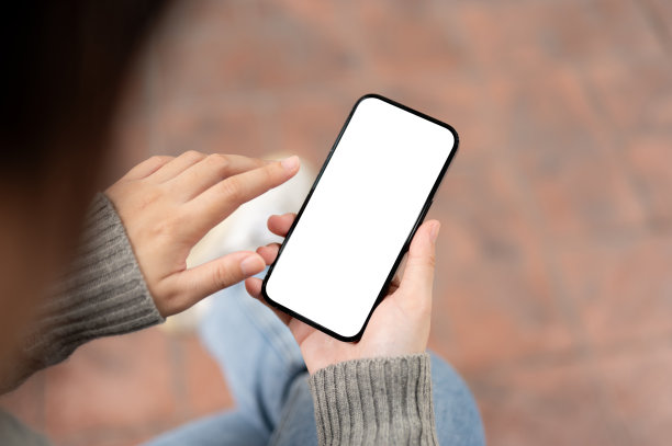 一位女士坐在户外使用智能手机的特写照片。智能手机模型。图片下载