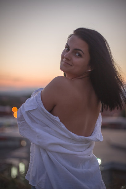 城市上空夕阳下自信快乐的年轻女子的肖像图片下载