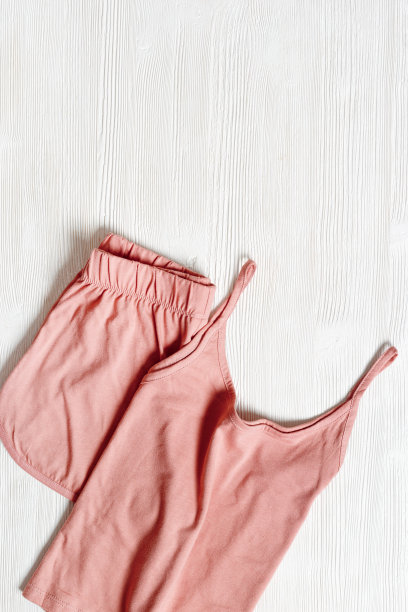 白色木制背景上的粉色睡衣。夏夜西装睡觉，折叠的衣服，背心和短裤俯视图照片。女士睡衣最小平躺式，舒适睡眠图片下载