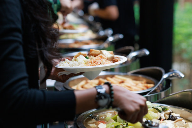 这张裁剪过的图片捕捉到了商人们用服务钳从自助餐队伍中小心翼翼地挑选食物。图片下载