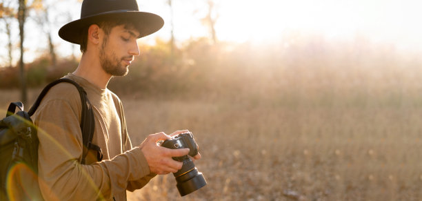 冒险摄影师在日落时分在秋天的山上散步，拍摄风景照片图片下载