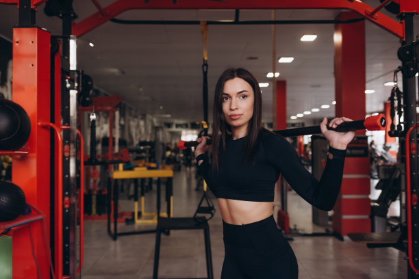 一个女运动员在健身房里举着杠铃的照片。图片下载