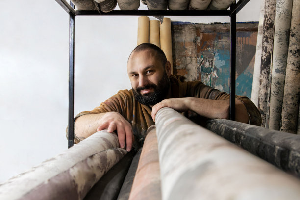 这位艺术家自豪地摆着他的画布，为摄影师加工。在他的房间里画背景，过着艺术家的生活。个体户画家看着相机愉快地库存照片图片下载