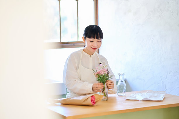 年轻女子欣赏花瓶里的花图片下载