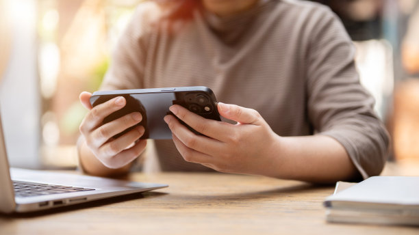 一名亚洲女性坐在咖啡馆里用智能手机看视频的剪辑照片。图片下载