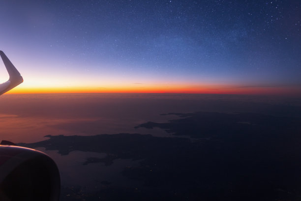 借助机翼和涡轮机，从飞机窗口眺望星空、西班牙大陆和日落。乘飞机旅行，概念。天空中美丽的日落。云中风景图片下载