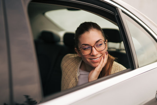 一张年轻女商人坐在汽车后座上的照片。图片下载