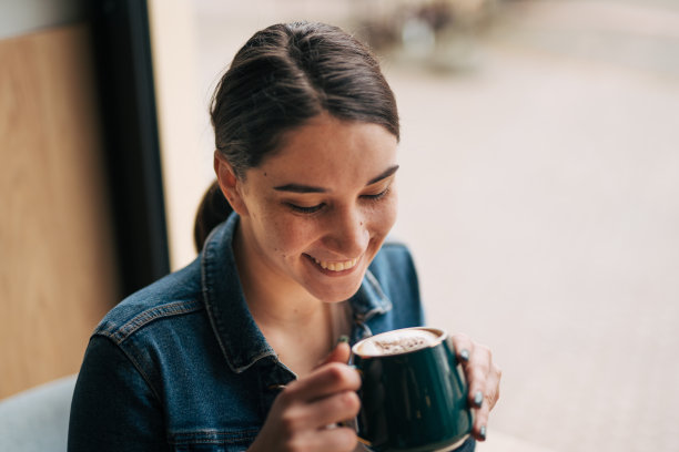 一张年轻女子坐在咖啡厅里享受咖啡的照片。图片下载