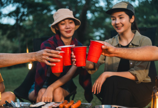 干杯!一群亚洲人朋友在大自然中露营，用软饮料和啤酒举杯祝酒。户外聚会在露营地自然森林背景在假日周末假期图片下载