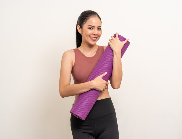 年轻美丽的亚洲女子与运动服拿着瑜伽垫孤立的白色背景。肖像迷人的运动妇女站立姿势锻炼锻炼在工作室。训练瑜伽的生活方式。图片下载