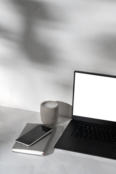 白色屏幕的笔记本电脑模型，笔记本，手机，大理石灰色桌面背景上的蜡烛，抽象阳光阴影的白色混凝土墙，优雅的商业品牌模板图片下载