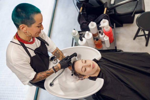 富有创意的女理发师正在美容院为年轻女子洗头。高质量照片图片下载