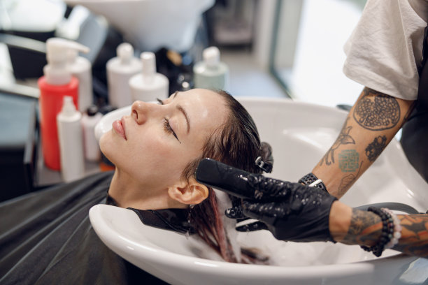 美发师在美容院给年轻女子洗头的特写。高质量照片图片下载