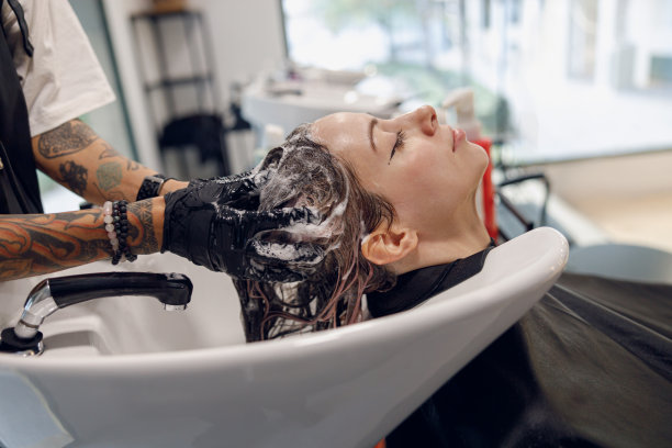 美发师在美容院给年轻女子洗头的特写。高质量照片图片下载