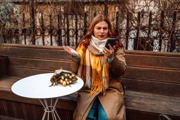 沮丧的女人看起来很担心被拒绝的女孩在城市咖啡馆外面用智能手机等男朋友图片下载