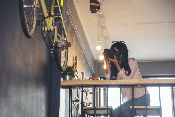 亚洲妇女拿着老式胶片相机拍照。微笑的女摄影师看着专业户外相机拍摄的照片。年轻女子在绿色自然公园拍照。美女爱好图片下载