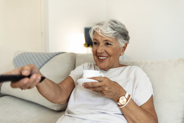 年长的女士，沙发和咖啡放松与滑稽，喜剧或快乐的我的时间在酒店休息室微笑。老太太，沙发和茶在家里的客厅里幸福地退休，疯狂地笑。图片下载