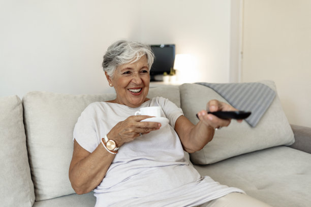 年长的女士，沙发和咖啡放松与滑稽，喜剧或快乐的我的时间在酒店休息室微笑。老太太，沙发和茶在家里的客厅里幸福地退休，疯狂地笑。图片下载