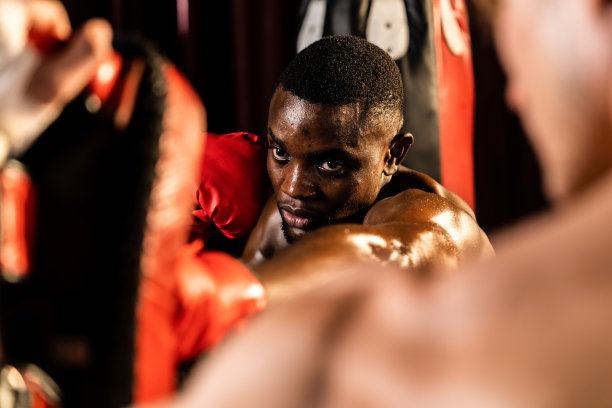 非裔美国黑人拳击手向戴拳击手套的教练或教练拳打脚踢。动力图片下载
