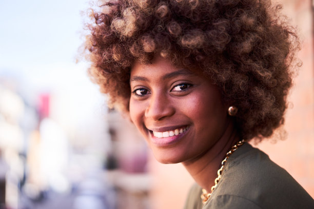 一幅欢快的非洲年轻女子看着镜头微笑的肖像。图片下载