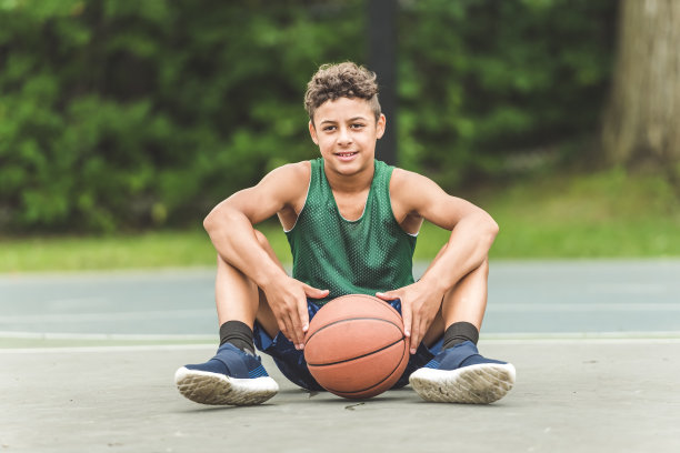 一个男孩在公园里打篮球的照片图片下载