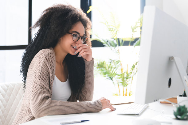 使用电脑时欢笑的快乐非洲年轻女性图片下载