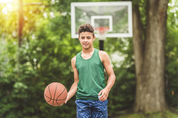 一个男孩在公园里打篮球的照片图片下载