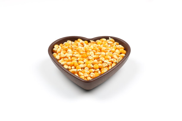 白色背景的木碗里装着未爆的爆米花。一种玉米，在受热时从玉米粒膨胀起来。黄色种子，可食用，生的和素食的食物。孤立的微距照片特写。图片下载