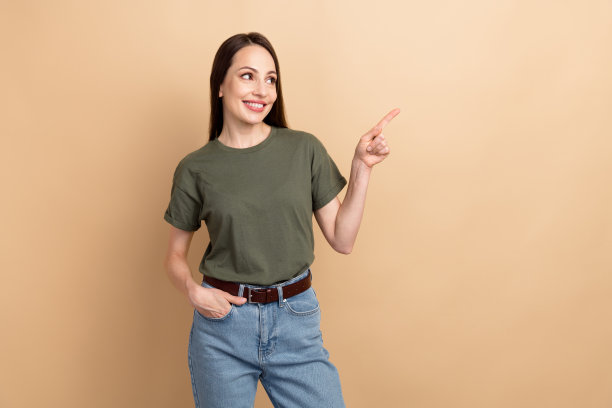 照片中的美女穿着t恤，直接手指空白的空间看关于合作的命题，孤立在米色背景上图片下载