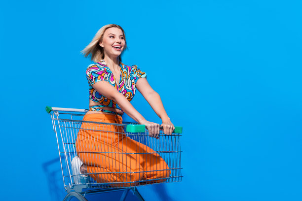 照片中乐观的女孩飘动着头发，快速地骑在电车上，看着蓝色背景上孤立的命题空间图片下载