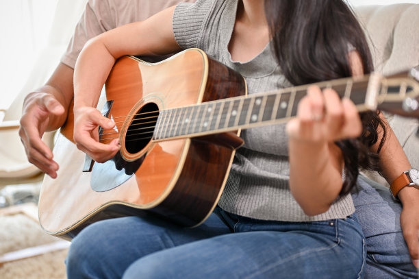 一个剪短的照片，一个男朋友正在家里教他的女朋友弹吉他。图片下载