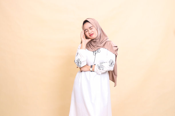 一名印度尼西亚穆斯林成年妇女的偷拍照片，她戴着头巾，因为头痛而闭上眼睛。用于广告、健康、科学和斋月图片下载