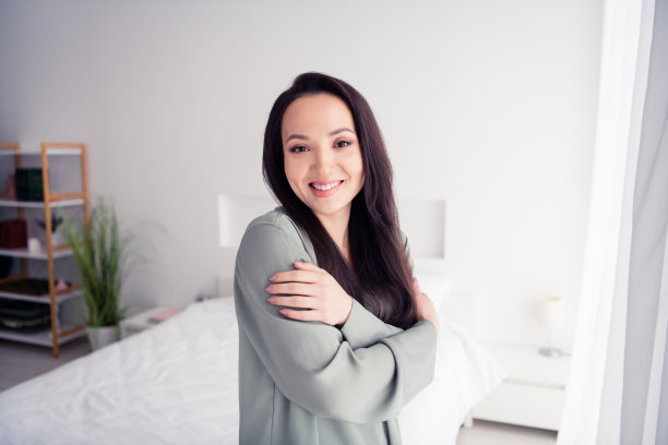 可爱的年轻女士的照片肖像拥抱自己的肩膀温暖穿着时尚的灰色睡衣隔离在白色的卧室室内图片下载