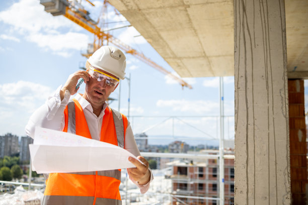 一个中年白人工程师在工地拿着蓝图打电话的照片图片下载